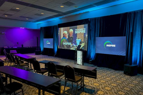 A conference room with rows of chairs and a screen displaying
