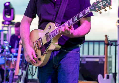 A person playing an electric guitar on stage during a live music performance outdoors.