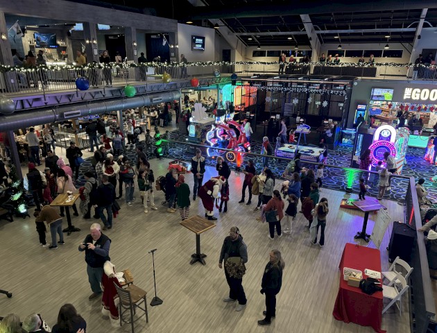 A busy arcade or entertainment venue with people mingling, playing games, and enjoying festivities.