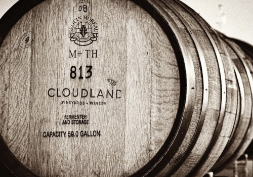 The image shows a stack of wooden barrels labeled 