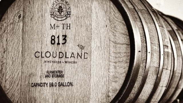 The image shows a stack of wooden barrels labeled 