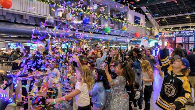 People celebrating indoors with colorful confetti and balloons, creating a festive atmosphere.