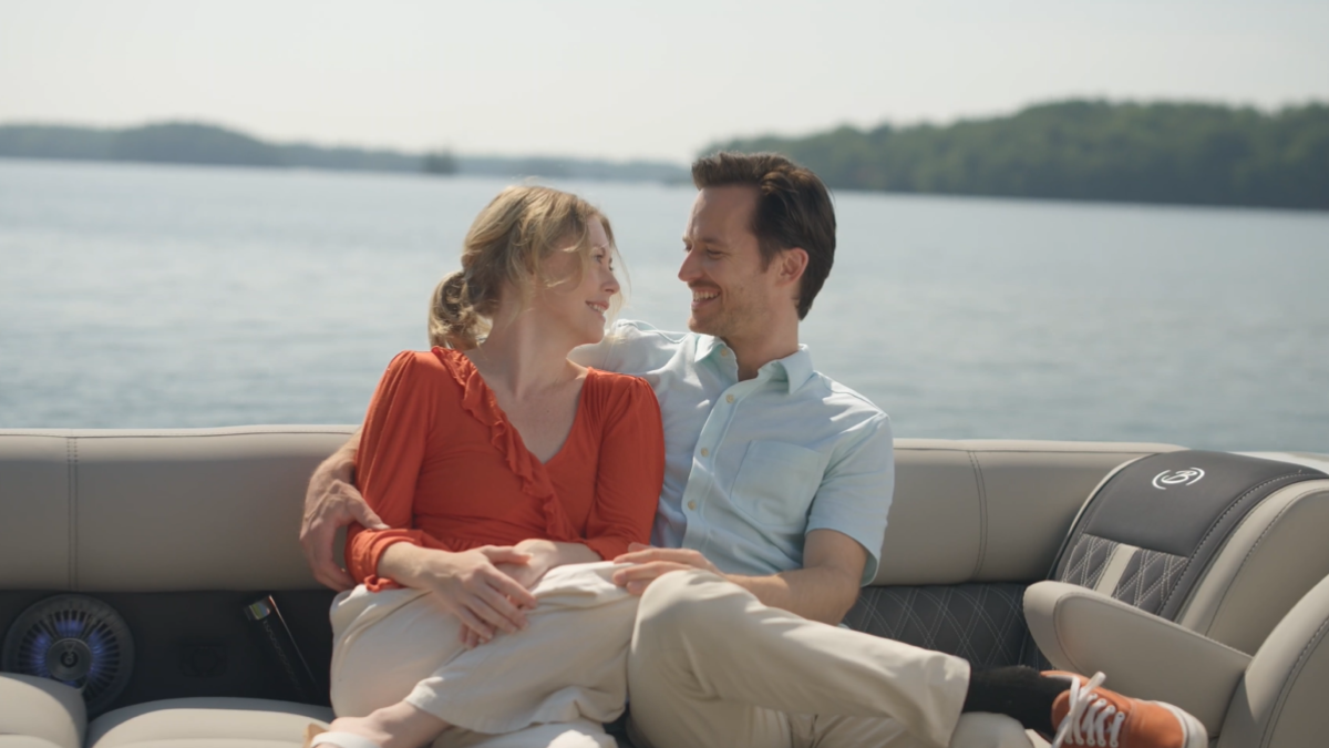 A couple sitting together on a boat, smiling and enjoying a sunny day on the water.