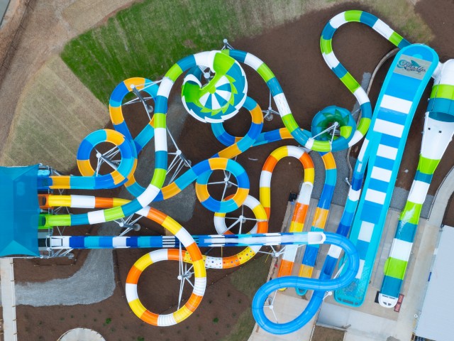 An aerial view of colorful water slides at a water park, including spirals, straight drops, and a large enclosed tube slide.