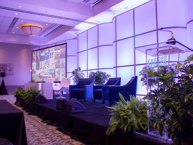 A conference room with a stage setup, featuring chairs, podium with 
