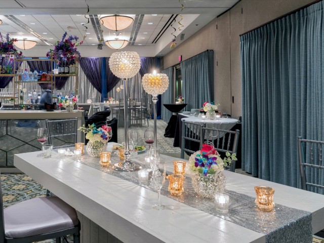 This image shows a decorated banquet hall with elegant tables, floral centerpieces, crystal glassware, and candles, creating a festive atmosphere.