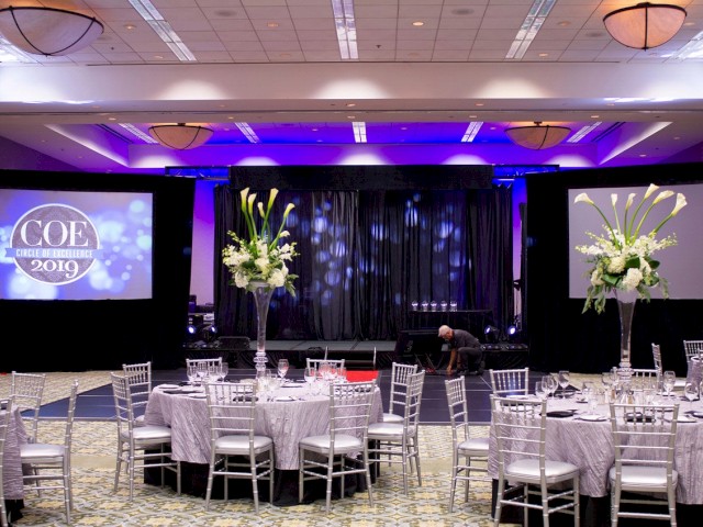 A decorated event venue with a stage, large screens displaying 