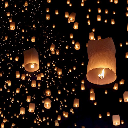 Floating lanterns illuminate the night sky, creating a stunning and magical scene.