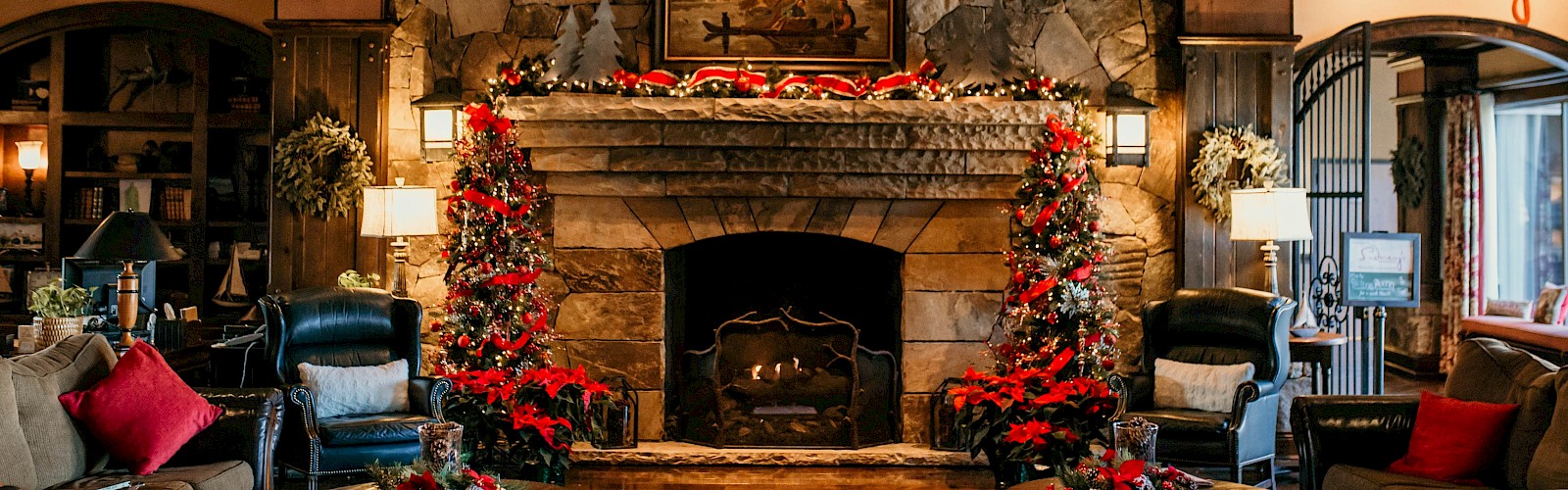 A cozy living room with a stone fireplace, festive decorations, and comfortable seating creates a warm, inviting atmosphere.