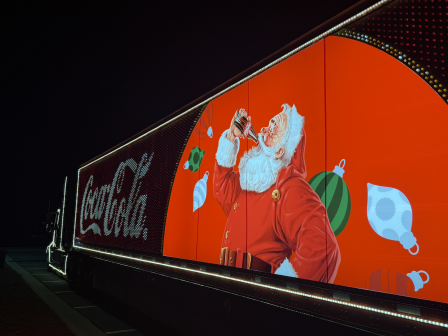 A festive digital billboard shows Santa drinking a soda with Christmas ornaments and a Coca-Cola sign nearby.