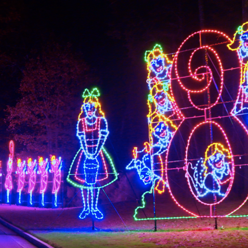 Colorful holiday LED light display features cheerful snowmen, a clown, and festive figures along a curved path.