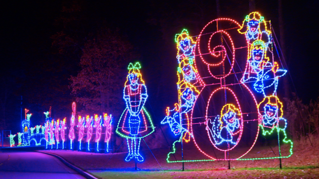 Colorful holiday LED light display features cheerful snowmen, a clown, and festive figures along a curved path.