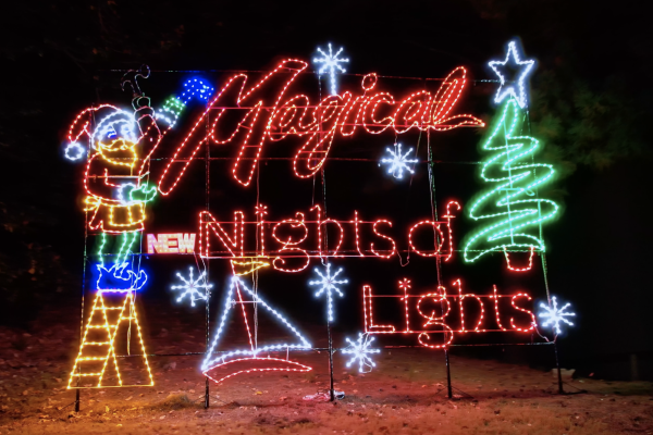 Colorful neon holiday display reading “Magical Nights of Lights” with a star, tree, sled, sleigh, and ornaments glowing at night.