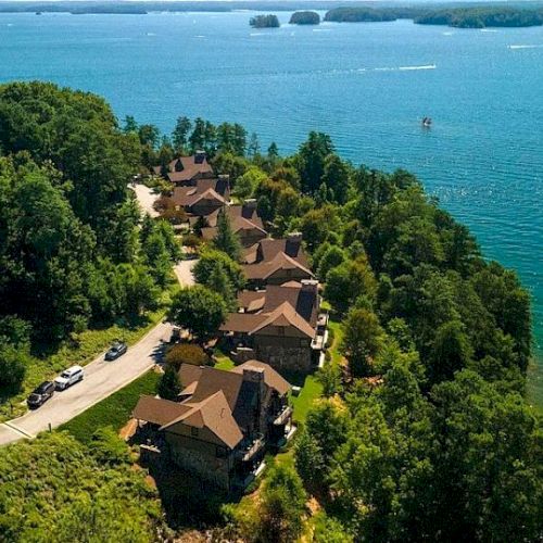 Aerial view of a lakeside residential area with green trees and clear water.