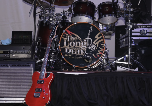 A stage setup with a red electric guitar, a drum kit with 