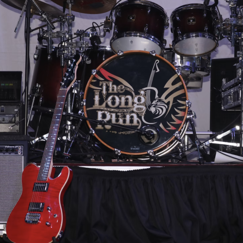 A stage setup with a red electric guitar, a drum kit with 