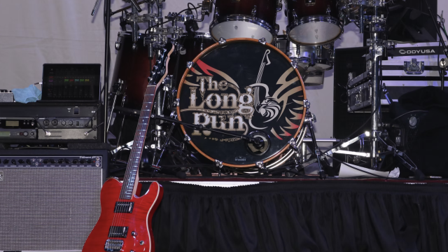 A stage setup with a red electric guitar, a drum kit with 