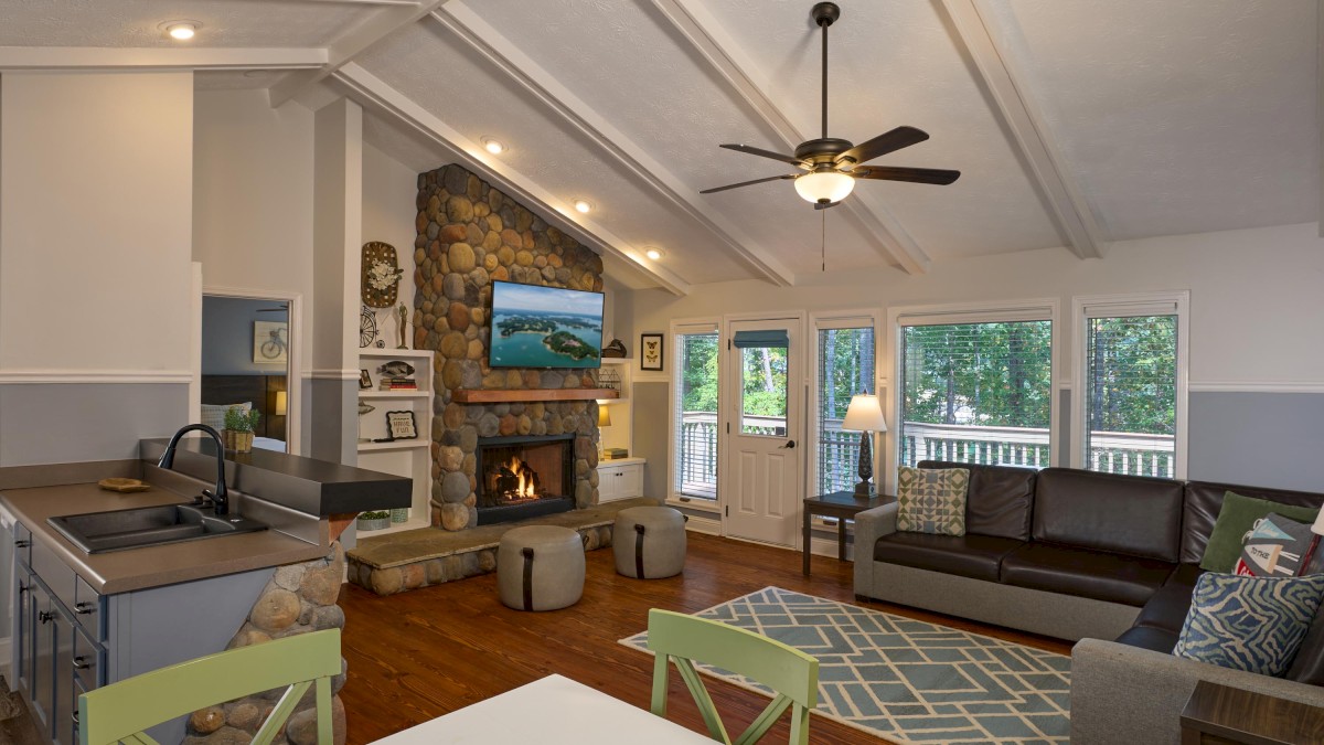 A cozy living room with a stone fireplace, large windows, and a mix of modern and rustic decor.