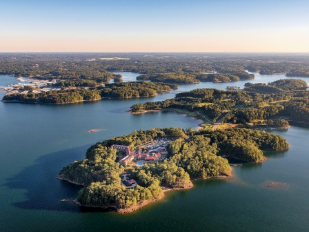 An aerial view of a large lake with multiple islands covered in trees, some with buildings and bridges connecting them.
