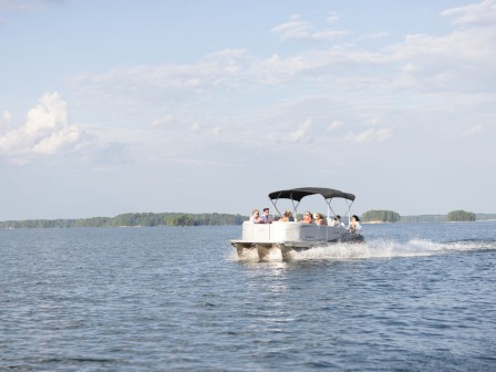 A group of people are enjoying a boat ride on a calm lake under a partly cloudy sky.