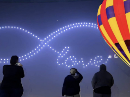 People watch a balloon and light display spelling out 