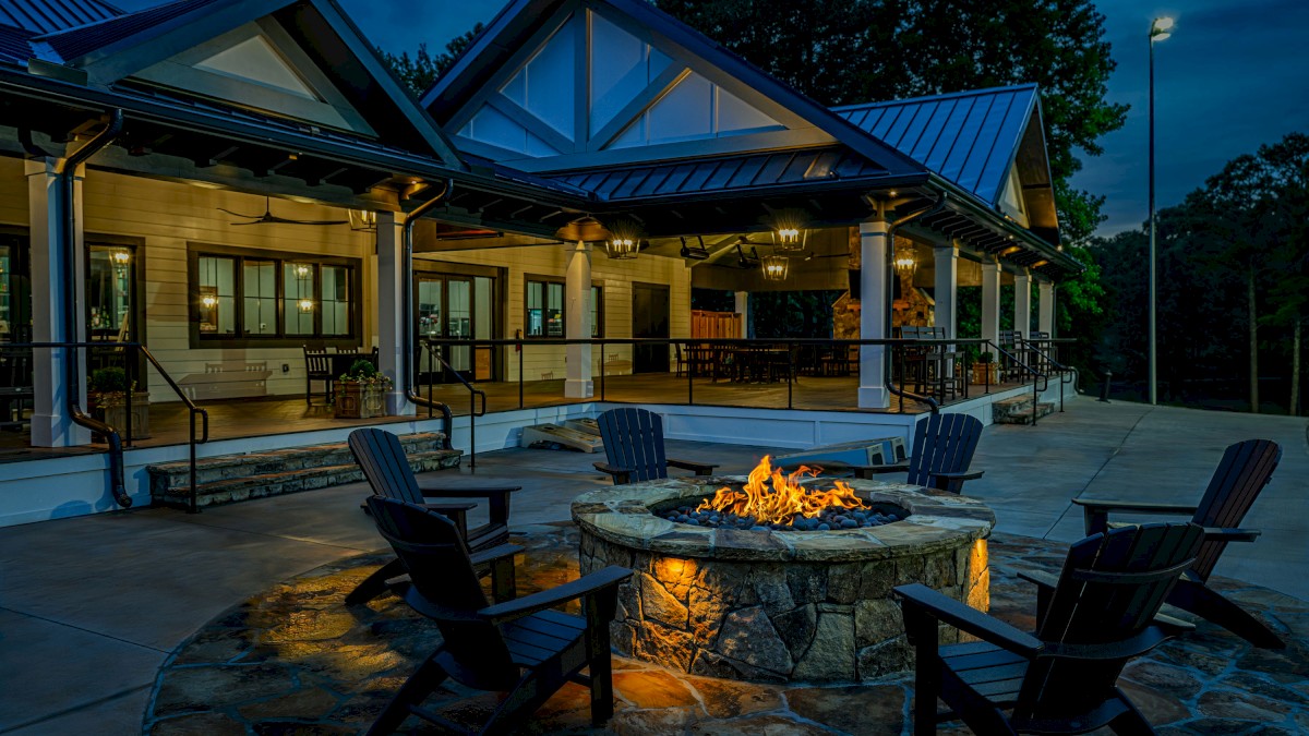 A cozy outdoor firepit area with chairs in front of a charming house at dusk.