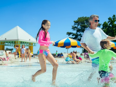 People enjoying a sunny day at the pool, playing and splashing water with family and friends.