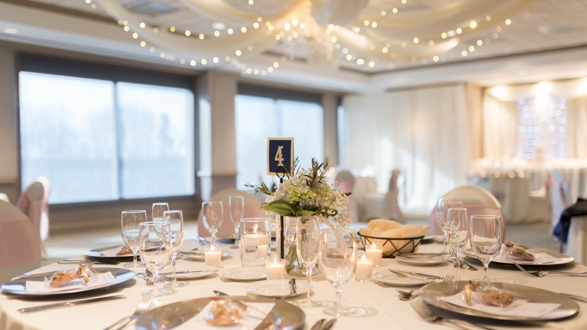 This is an elegantly decorated reception table set for a wedding or special event with floral centerpieces, candles, and place settings.
