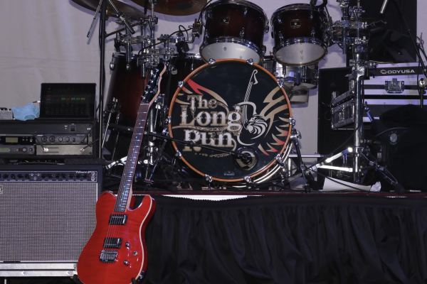 A music stage setup featuring a red electric guitar, a drum kit with 
