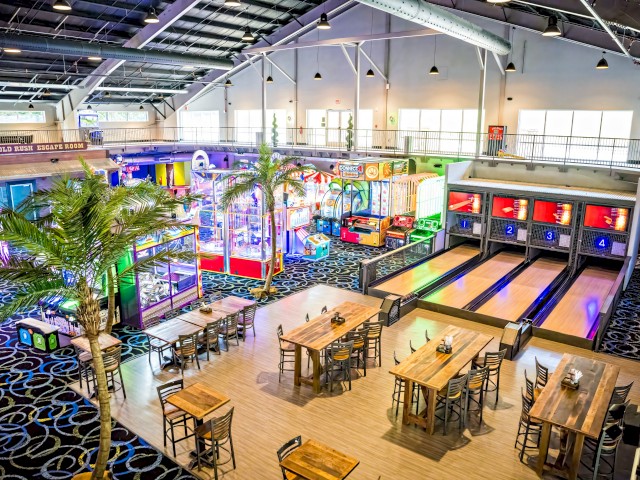 An indoor arcade features laser tag, a mini bowling alley, and various colorful gaming machines with seating areas.