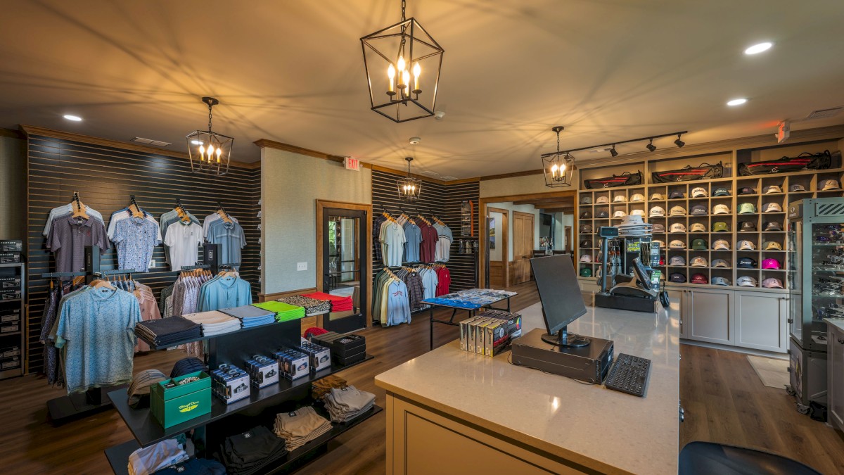 This image shows a golf shop interior with clothing, hats, and golf gear displayed neatly around the store.