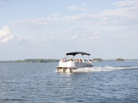 People enjoy boating on a calm, expansive lake under a partly cloudy sky.