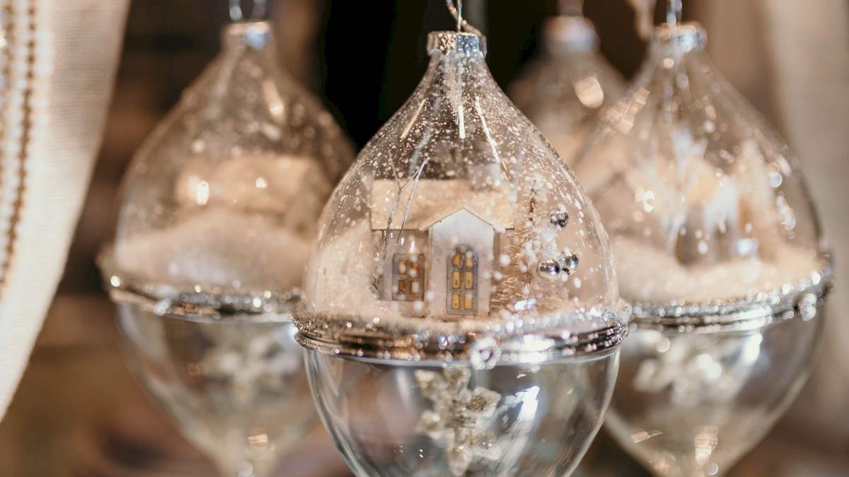 Decorative glass ornaments with miniature winter scenes inside, hanging on a display rack.