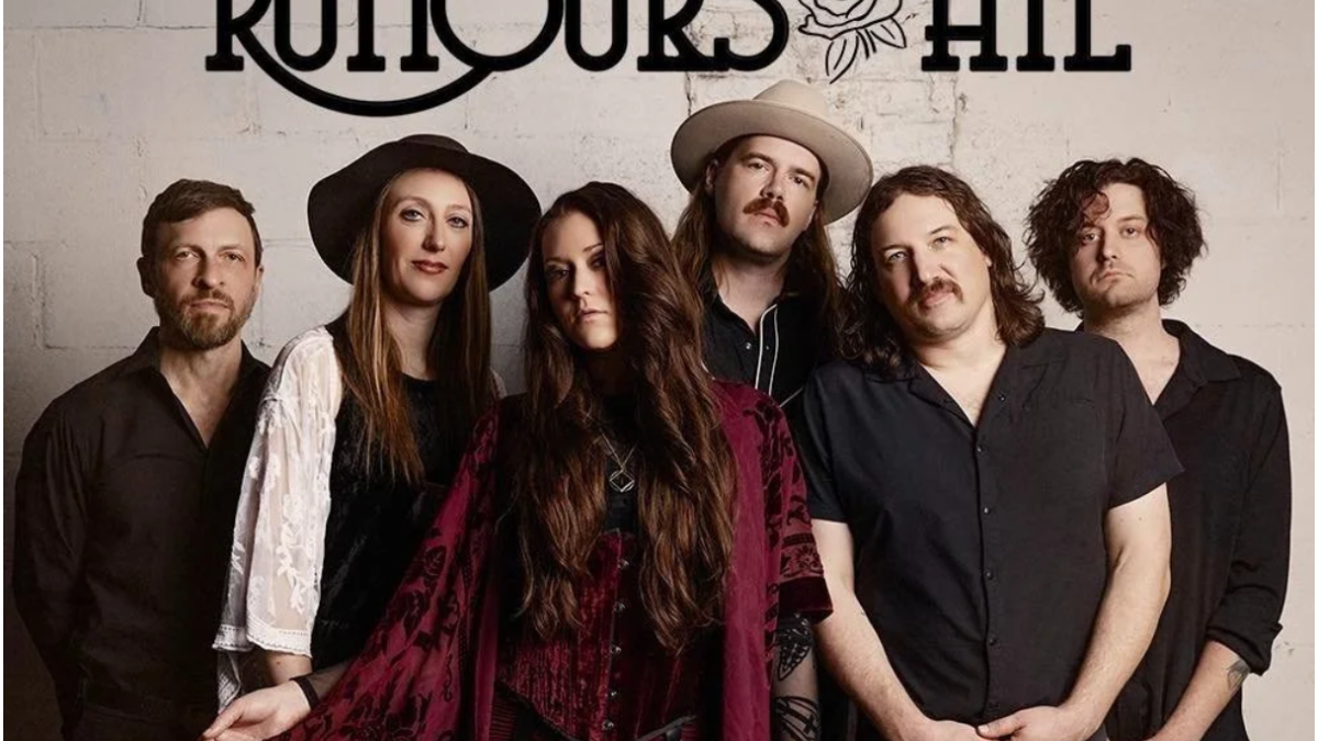 A band called Rumours At poses against a white wall, with the band name and a rose above them, dressed in dark and vintage-style clothing.