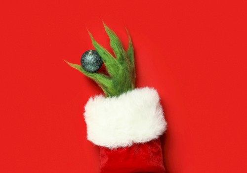 A festive puppet resembling a Christmas tree with a green spiky top, white fur cuff, and a blue ornament on a red background.