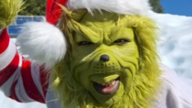 The image shows a creature with the face of the Grinch dressed in a Santa hat, smiling in a snowy outdoor scene.