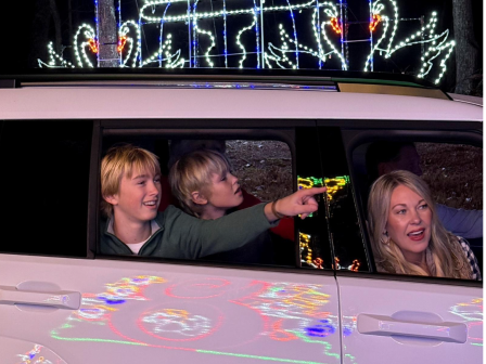 People enjoy a nighttime ride in a decorated vehicle, with colorful lights reflected on its surface.