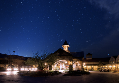 A well-lit building with a clock tower is set against a clear, starry night sky, creating a scenic and serene atmosphere.