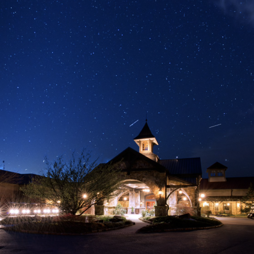 A well-lit building with a clock tower is set against a clear, starry night sky, creating a scenic and serene atmosphere.