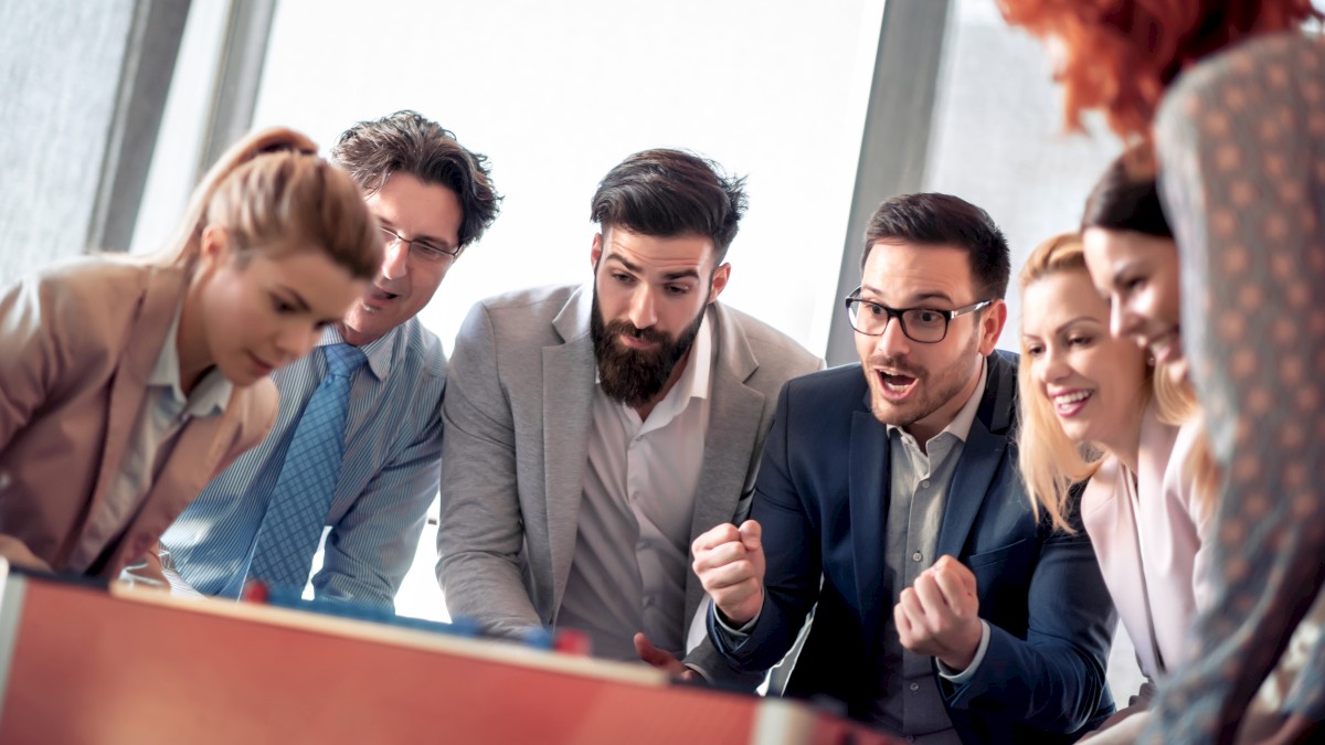 A group of businesspeople is excitedly looking at something off-camera, appearing engaged and enthusiastic in a professional setting.