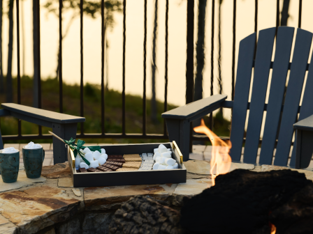 A summer evening at a firepit with s'mores, hot chocolate, and Adirondack chairs by a lake.