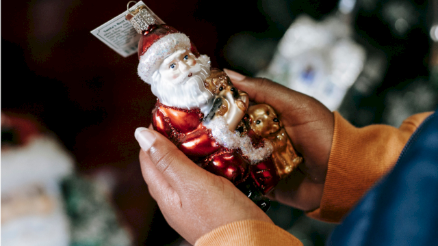 A person holding a Santa Claus ornament with teddy bears, ready for Christmas decorating.