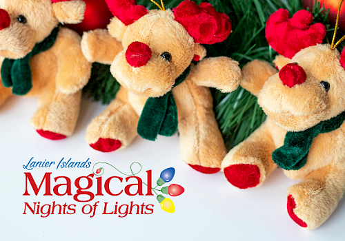 The image shows plush reindeer toys with red antlers and scarves, surrounded by pine branches and ornaments.