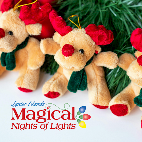 The image shows plush reindeer toys with red antlers and scarves, surrounded by pine branches and ornaments.