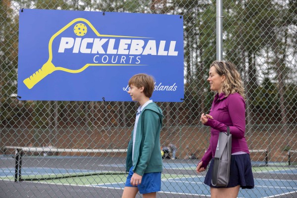 A woman and a child walk past a fence with a 