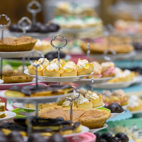 An array of desserts on tiered stands, including pies, cupcakes, and pastries, displayed in a colorful and inviting presentation.